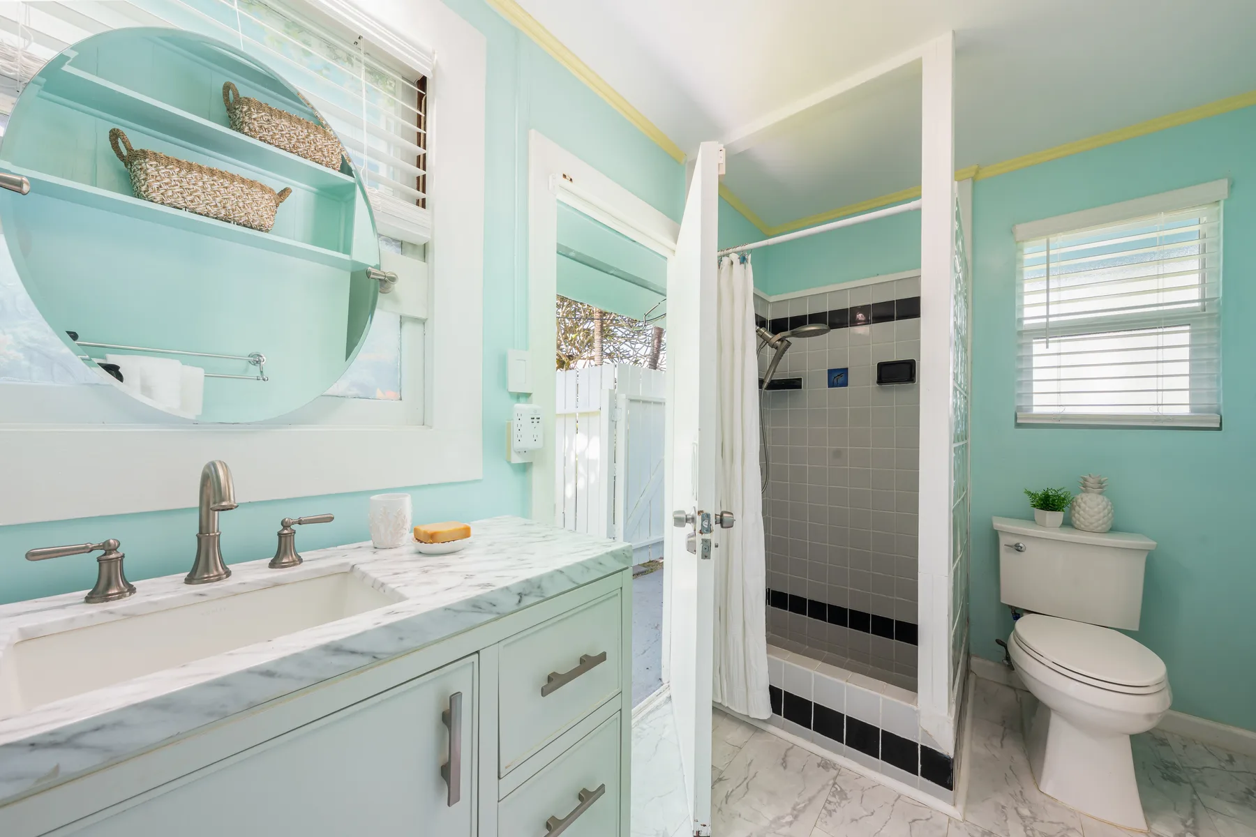 Un baño luminoso con lavabo, espejo, ducha e inodoro.