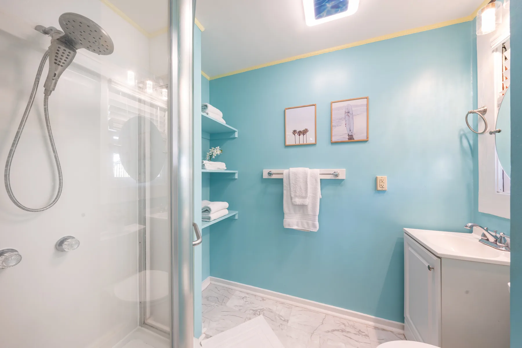 Un baño luminoso con una ducha acristalada y un lavabo con mueble.