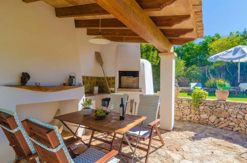 A covered outdoor dining area with a table and built-in barbecue.