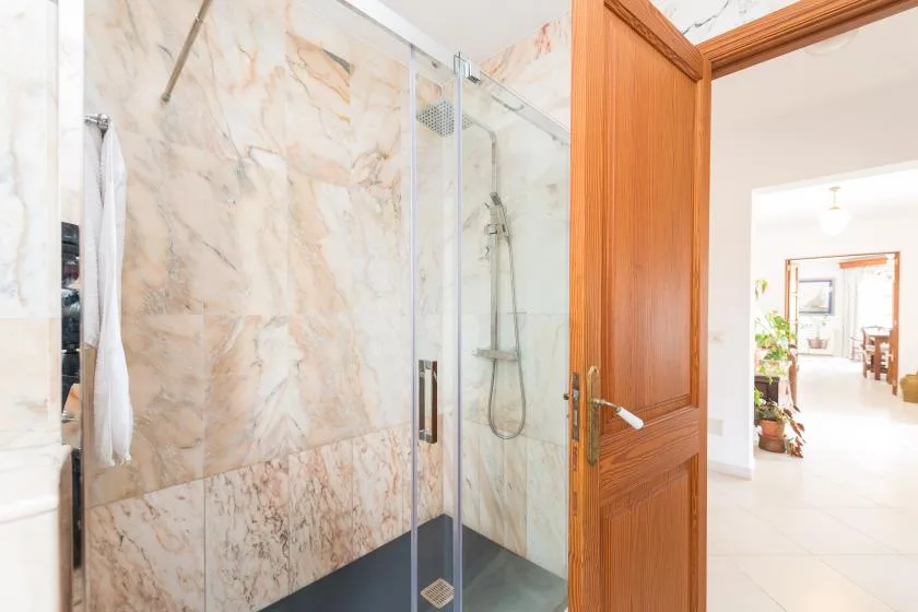 A bathroom with a glass shower beside an open wooden door.