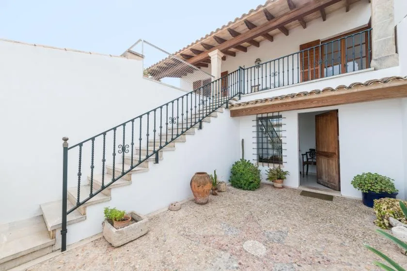 A sunlit courtyard with an exterior staircase and an open doorway.