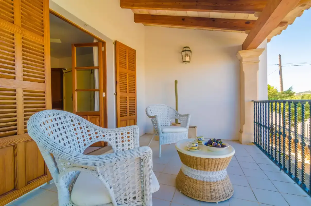 A covered terrace with wicker seating and a small round table.