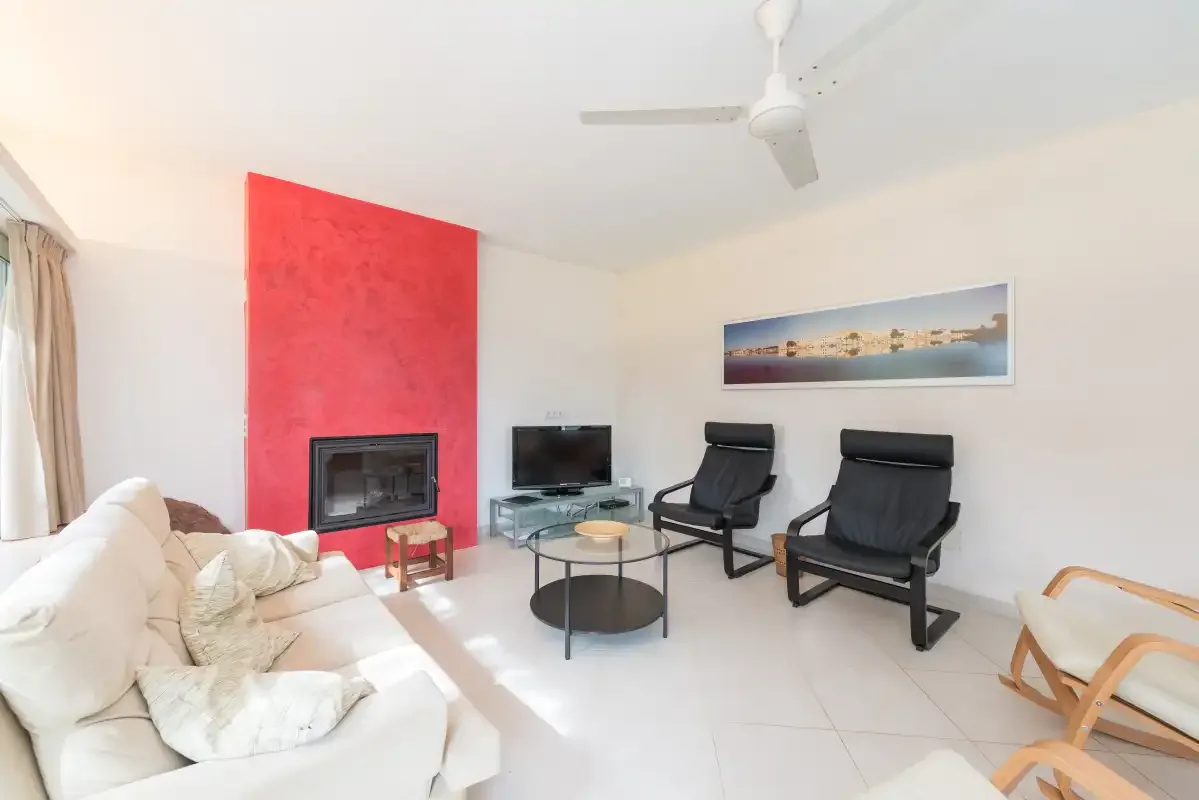 A living room with seating around a coffee table and a television.