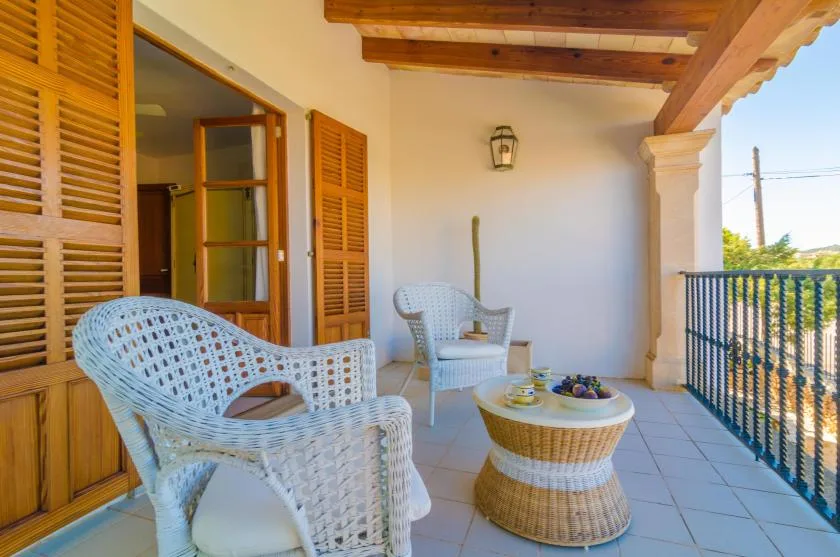 A covered outdoor seating area with woven chairs and a small round table.