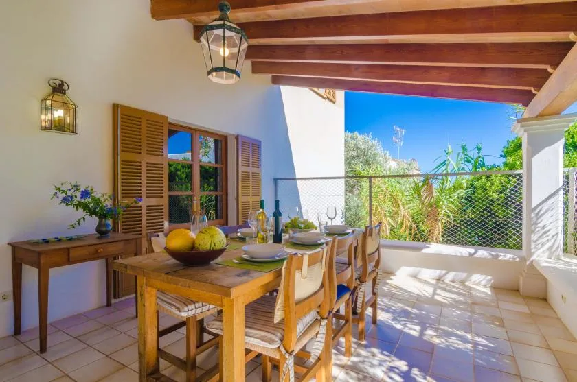A covered outdoor dining area with a wooden table and garden views.