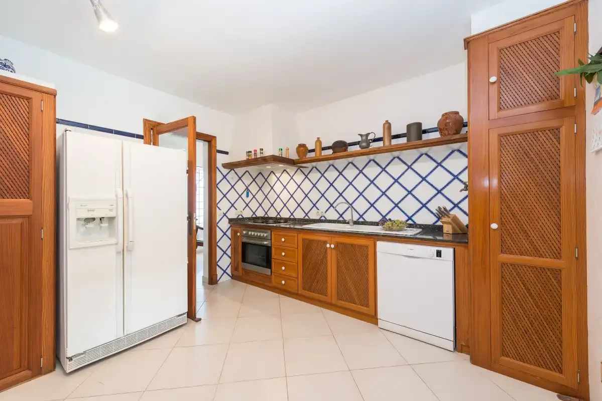 A kitchen with wooden cabinets, a tiled backsplash, and white appliances.