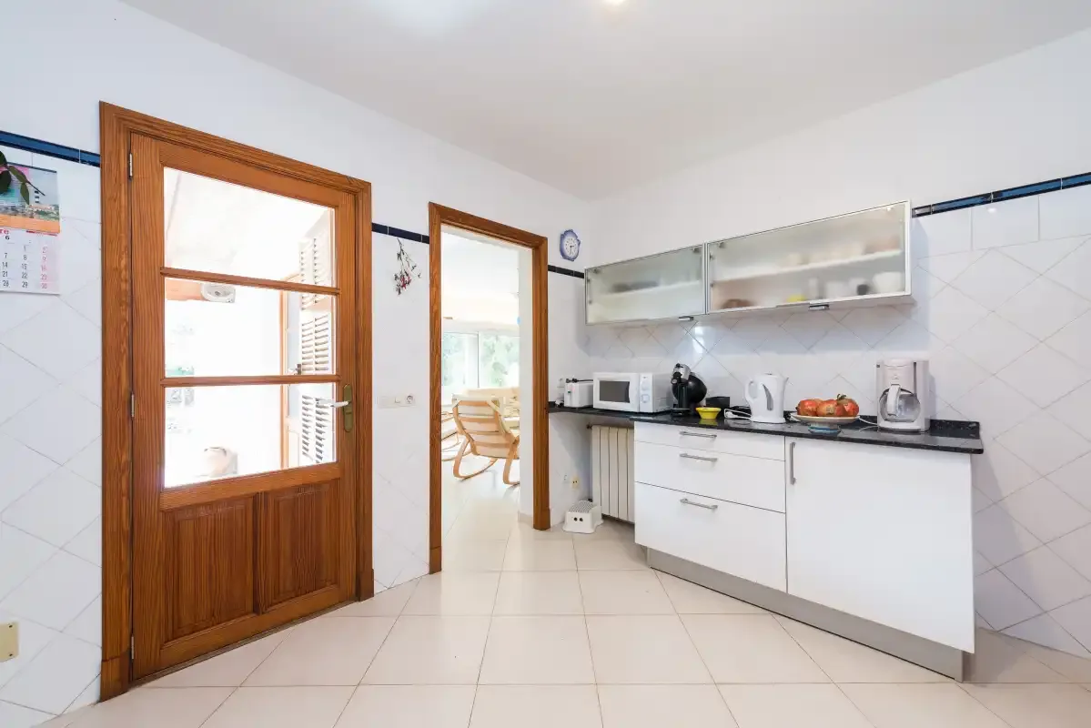 A bright kitchen with white cabinets and a countertop.