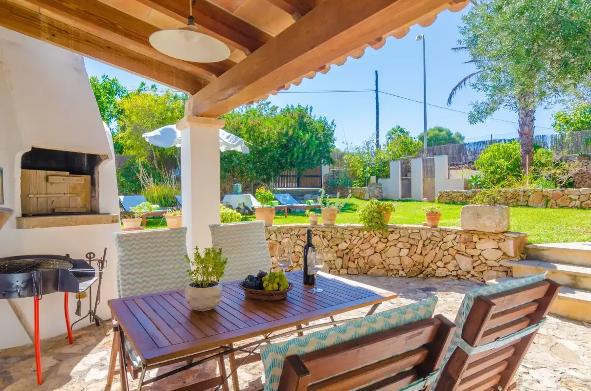 A covered outdoor dining area overlooks a garden and small pool.
