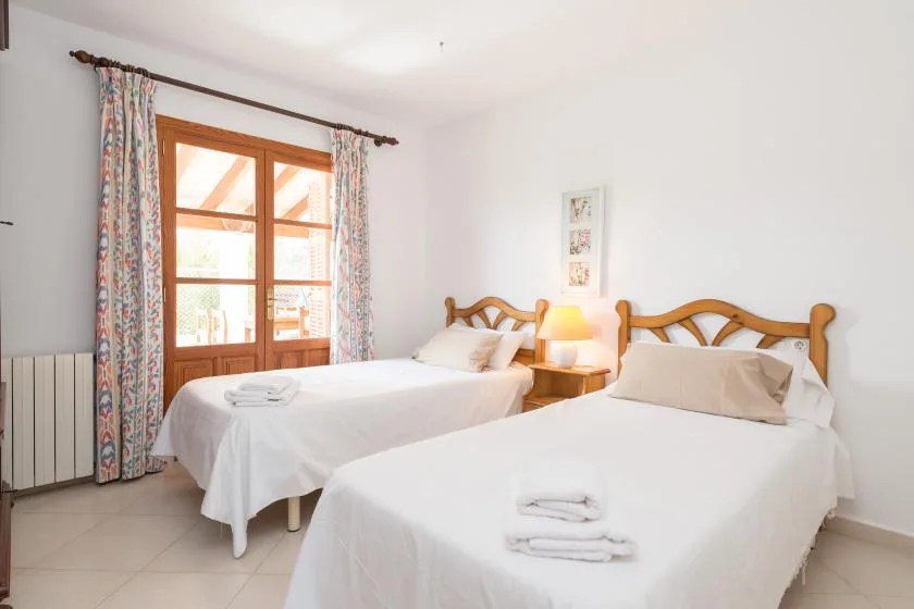 A bedroom with two beds, white bedding, and a window with patterned curtains.