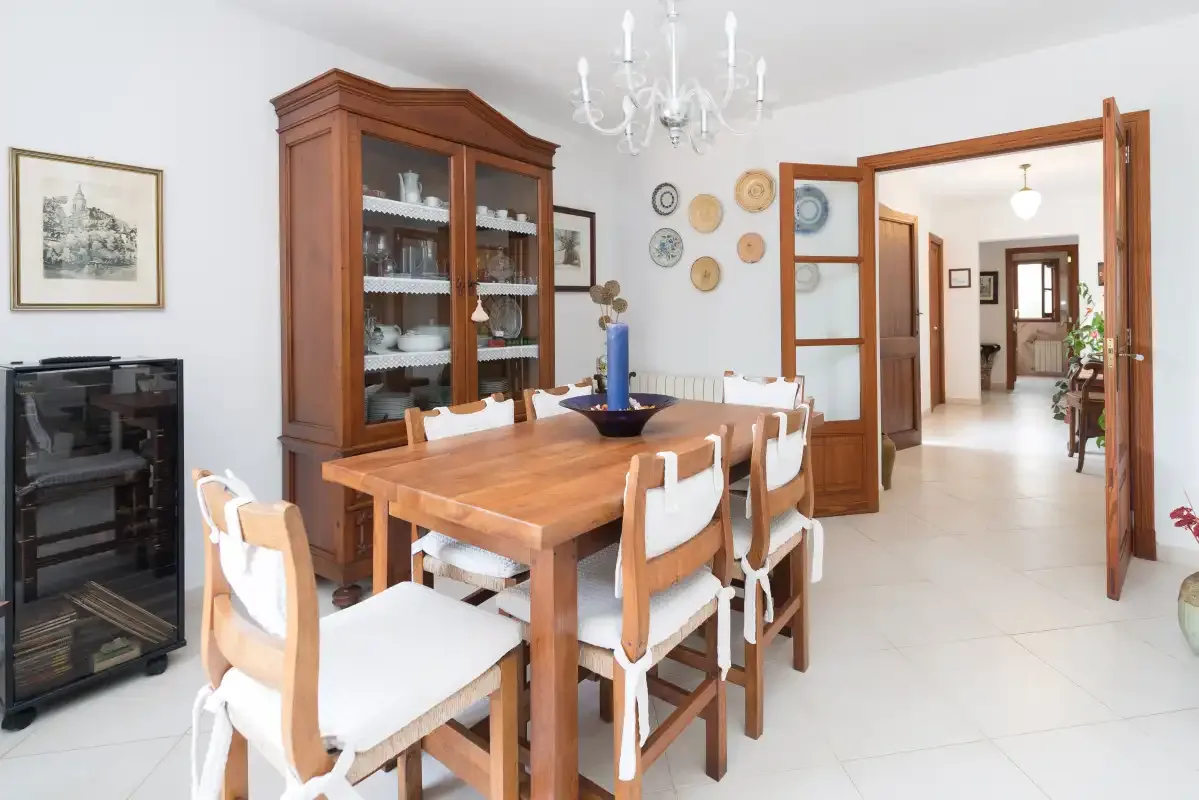 A dining room with a wooden table and chairs beside a glass-front cabinet.