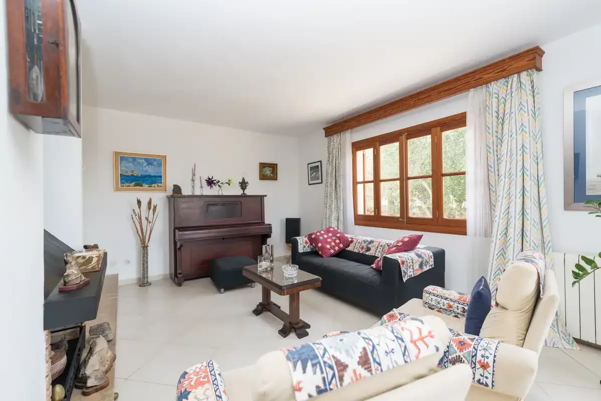 A living room with sofas, a piano, and a large window.