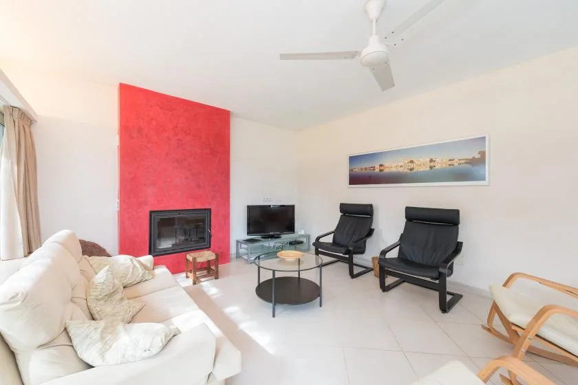 A bright living room with seating, a coffee table, and a television.