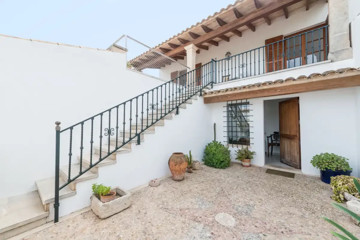 A courtyard with an exterior staircase leading to an upper balcony.