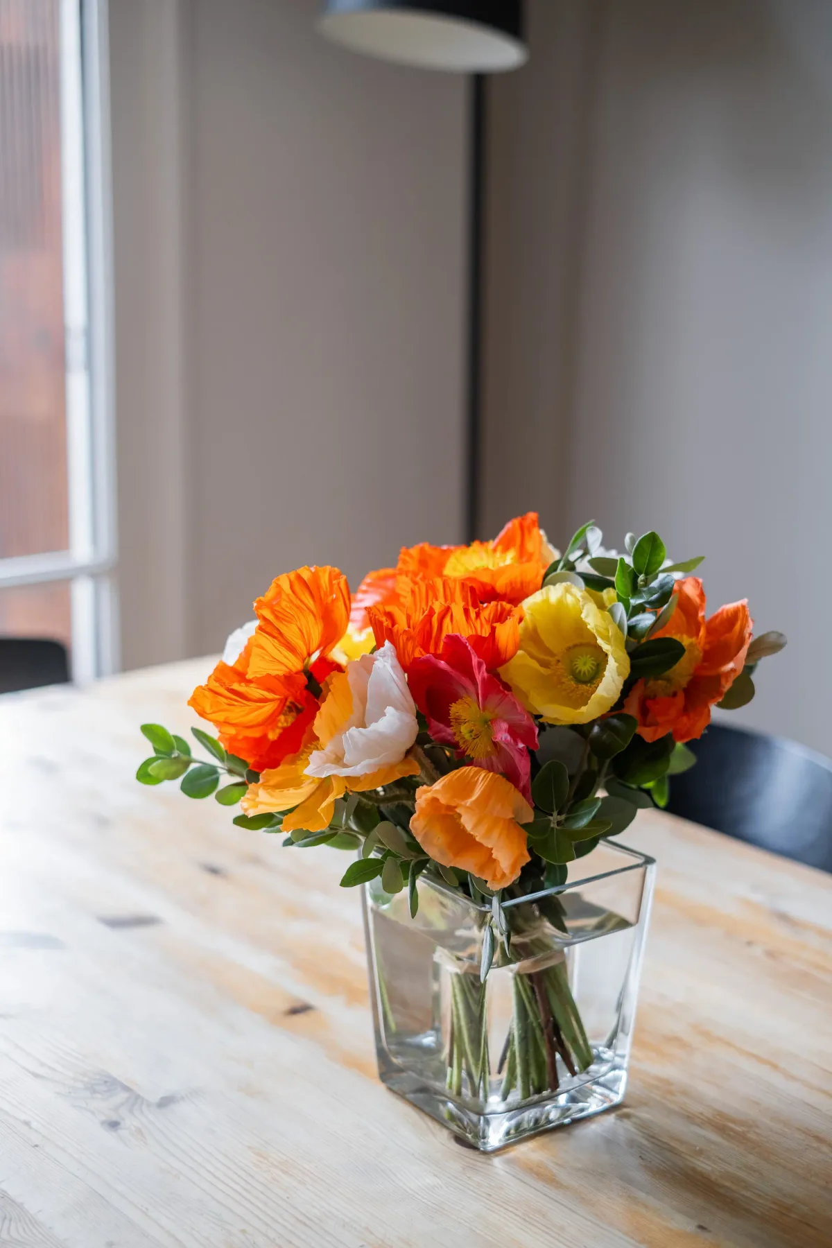 Un arreglo de flores coloridas está en un jarrón transparente sobre una mesa.