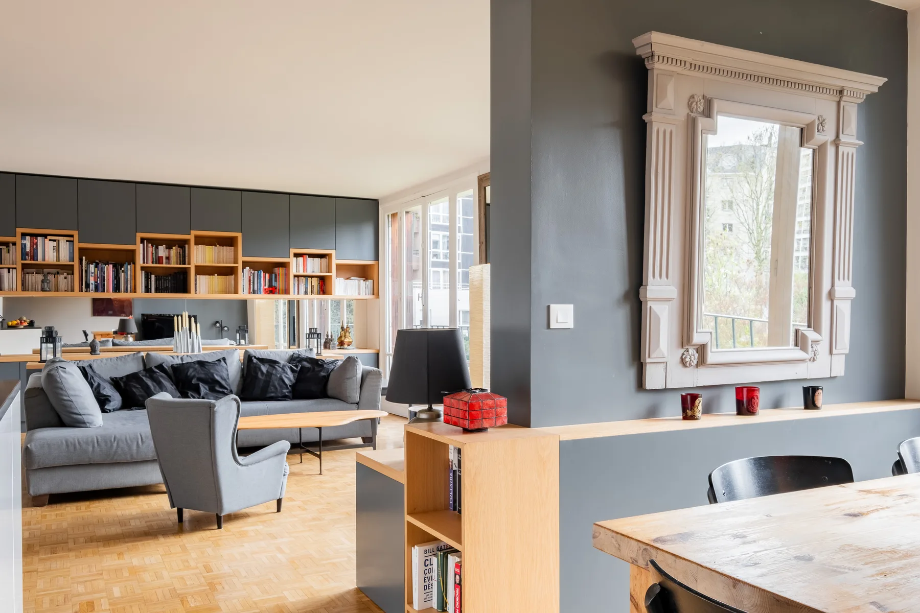 Una sala de estar y comedor de planta abierta con sofá, estanterías y una mesa.