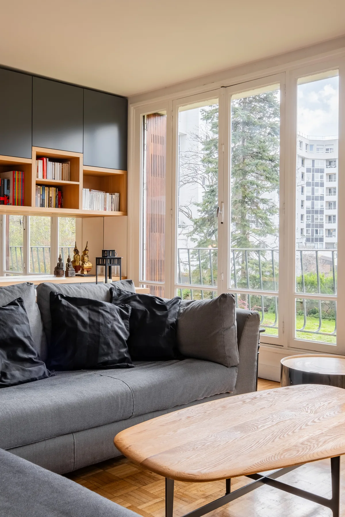 Una sala luminosa con asientos grises junto a ventanales y una mesa de centro de madera.