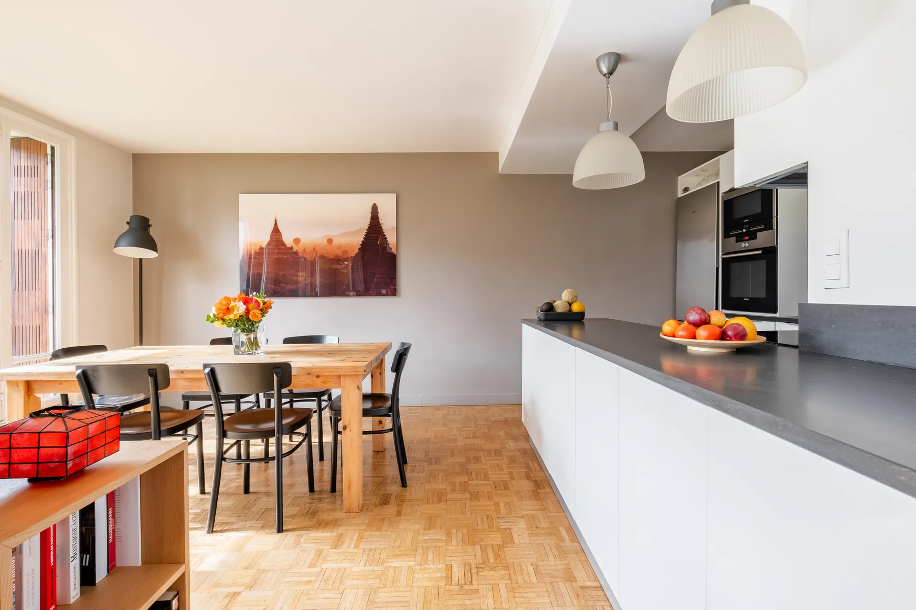 Comedor junto a una encimera de cocina, con una mesa de madera y fruta.