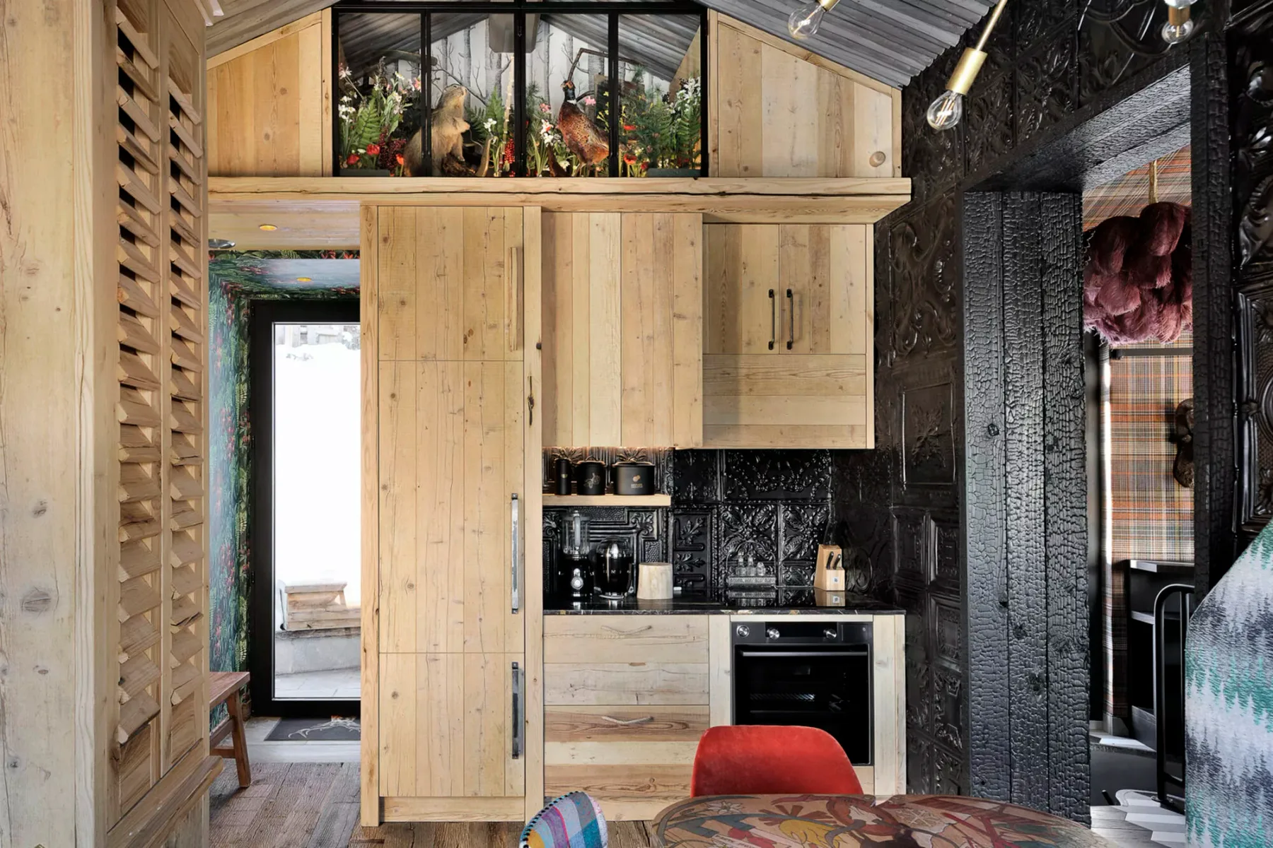 A rustic kitchen with wooden cabinets and dark patterned walls.