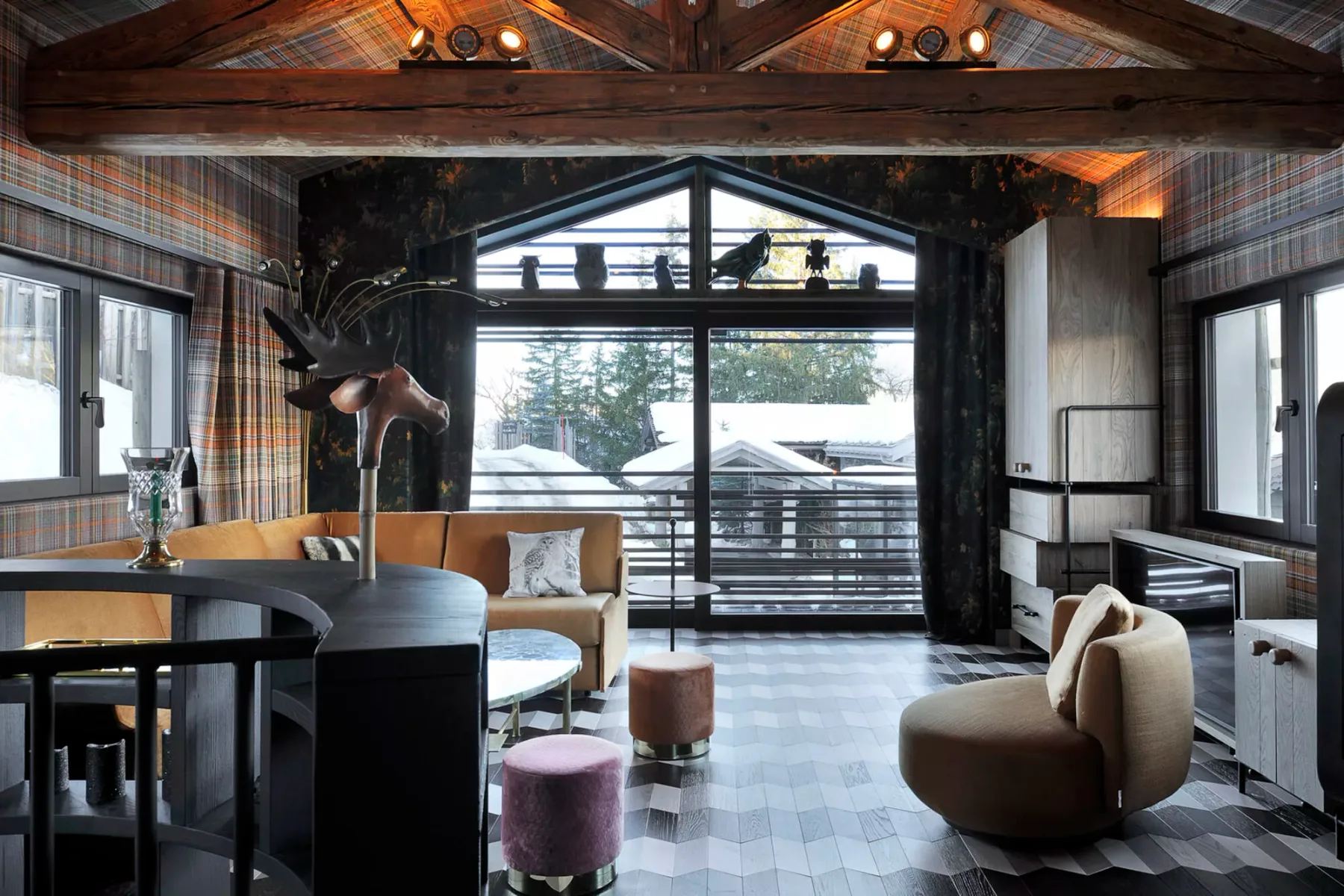 A timber-beamed living area opens onto a balcony through large windows.