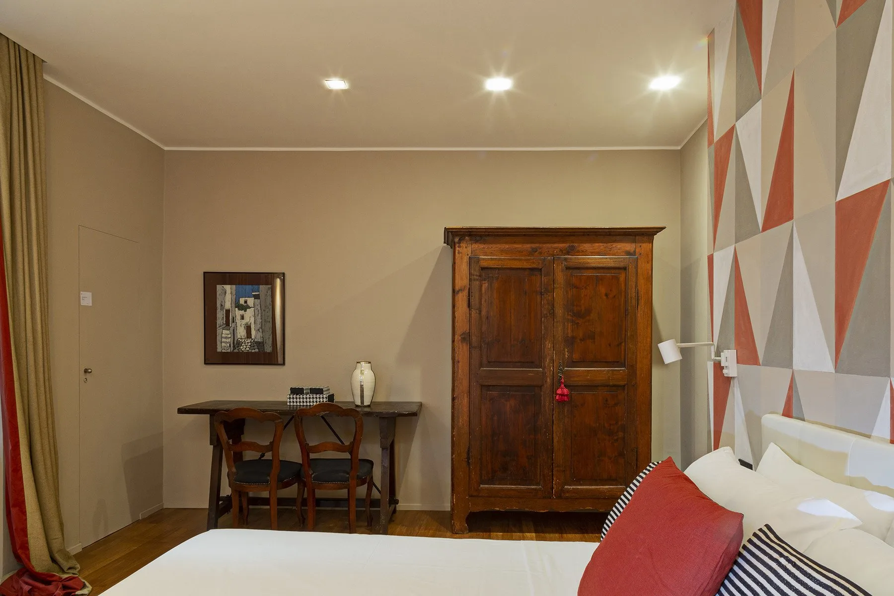 Un dormitorio con una cama, un armario de madera y un escritorio junto a la pared.