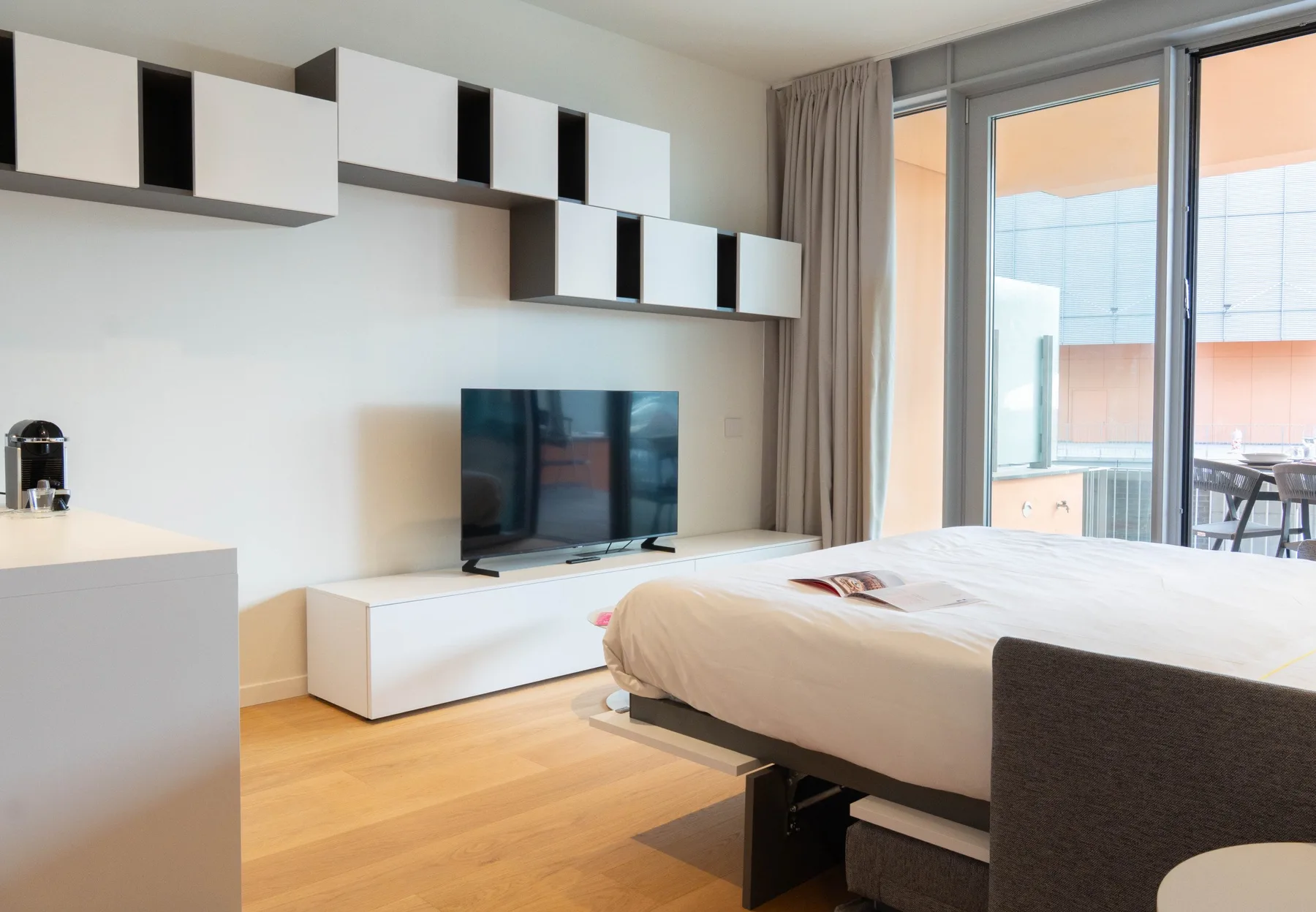 A bedroom with a bed, television, and large glass doors.