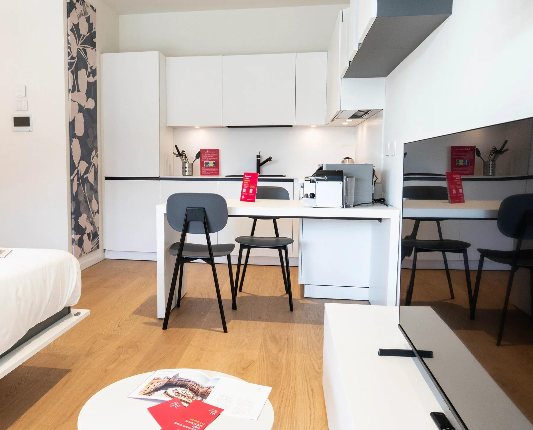 A bright kitchenette with white cabinets, a counter, and a small dining area.
