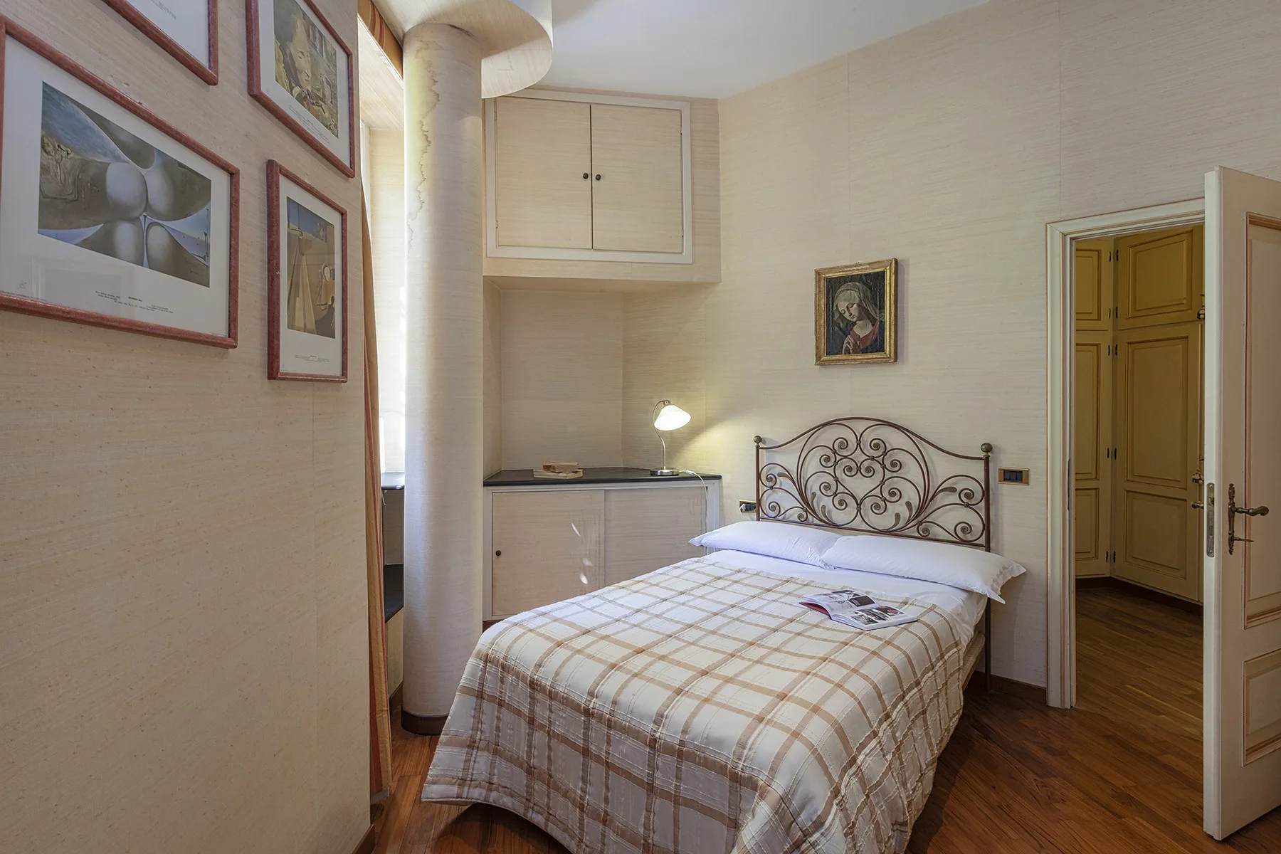 Un dormitorio con una cama tendida y cuadros en la pared.