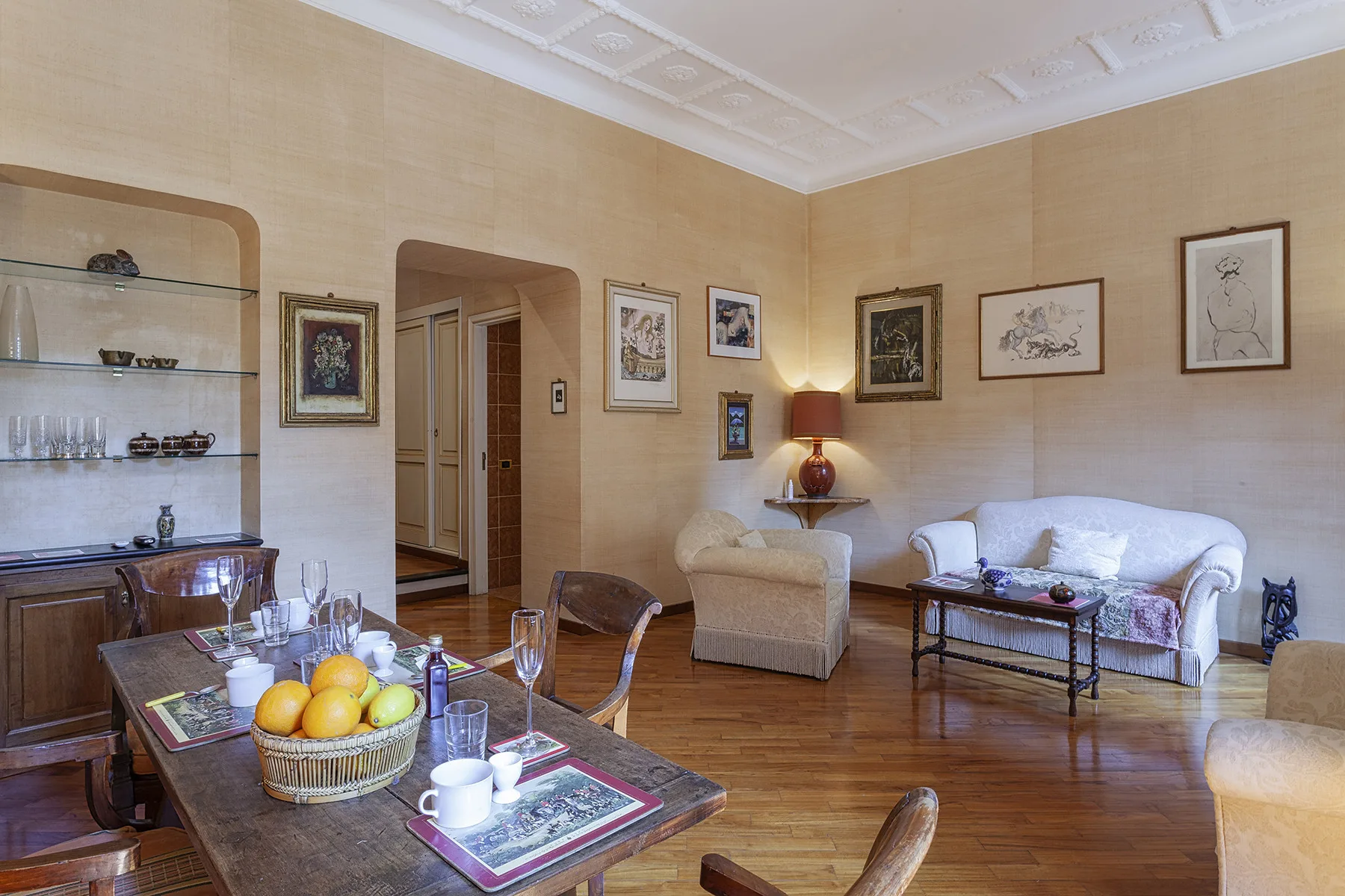 Una sala de estar con cuadros, una zona de asientos y una mesa de comedor.