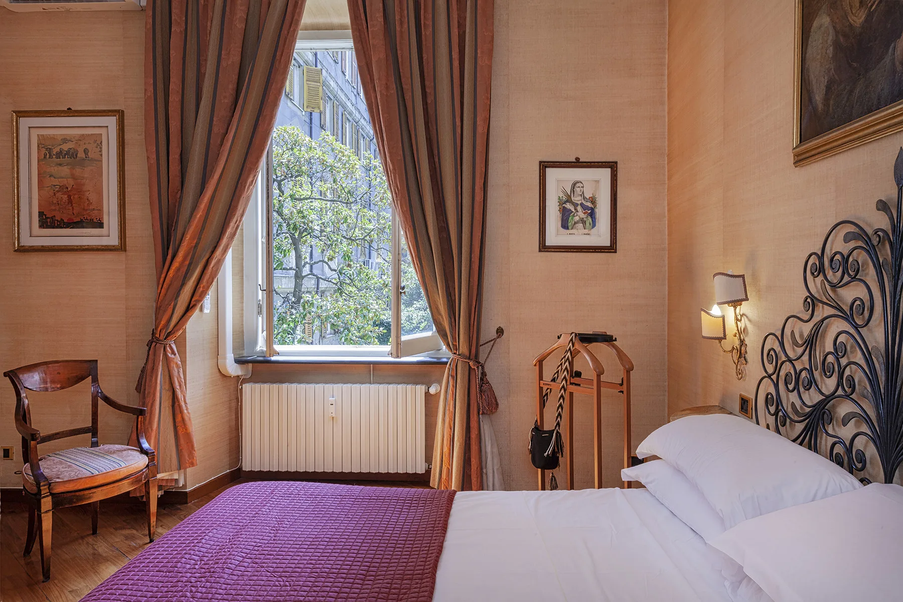 Un dormitorio con una cama, una ventana y cortinas largas.