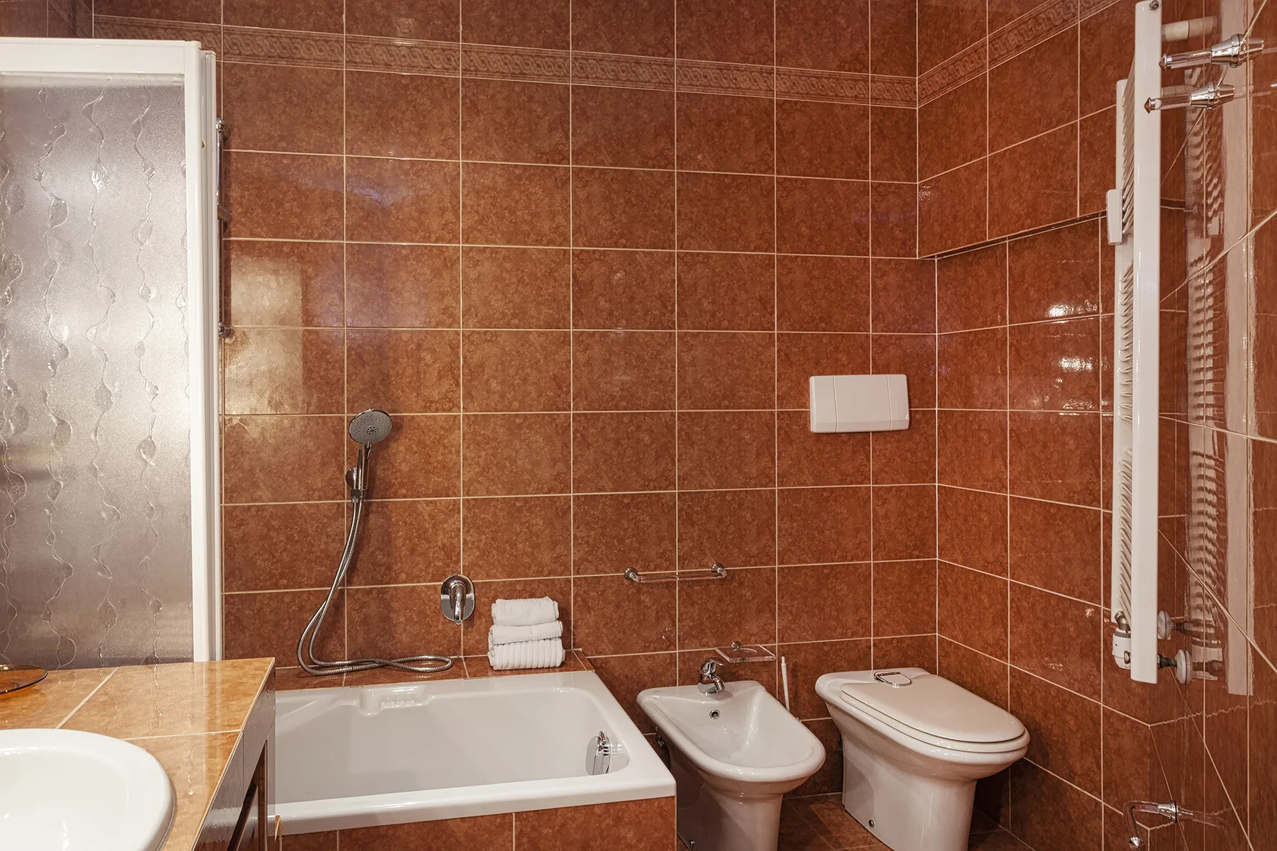 Un baño con paredes de azulejos, bañera, lavabo e inodoro.