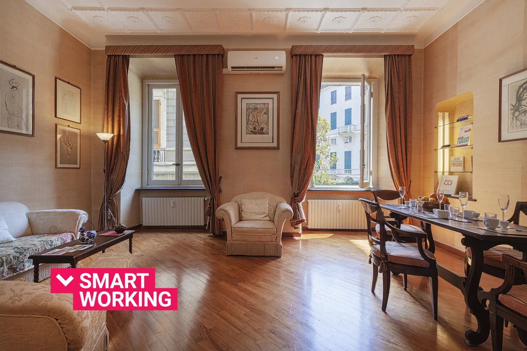 Una habitación amueblada con asientos y una mesa larga junto a ventanas altas.