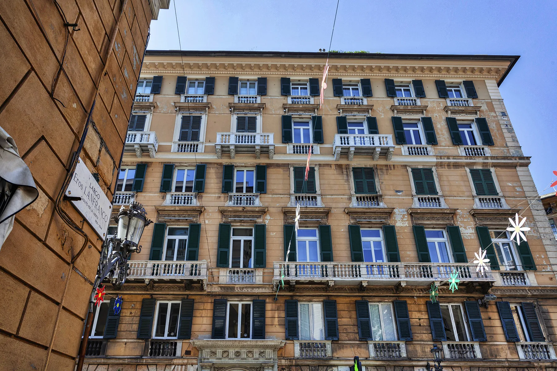 Un edificio de varias plantas con filas de ventanas y balcones se eleva sobre la calle.
