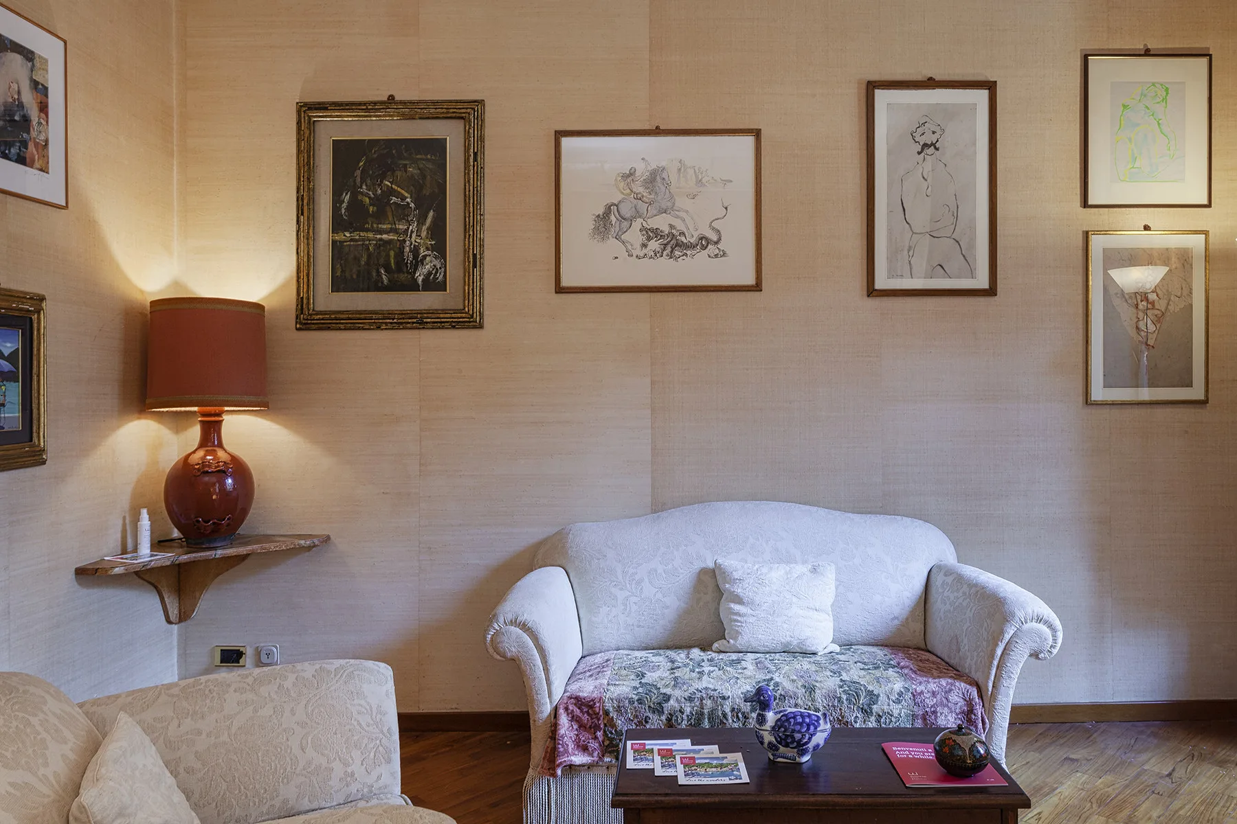 A living room with a pale sofa, framed artwork, and a table.