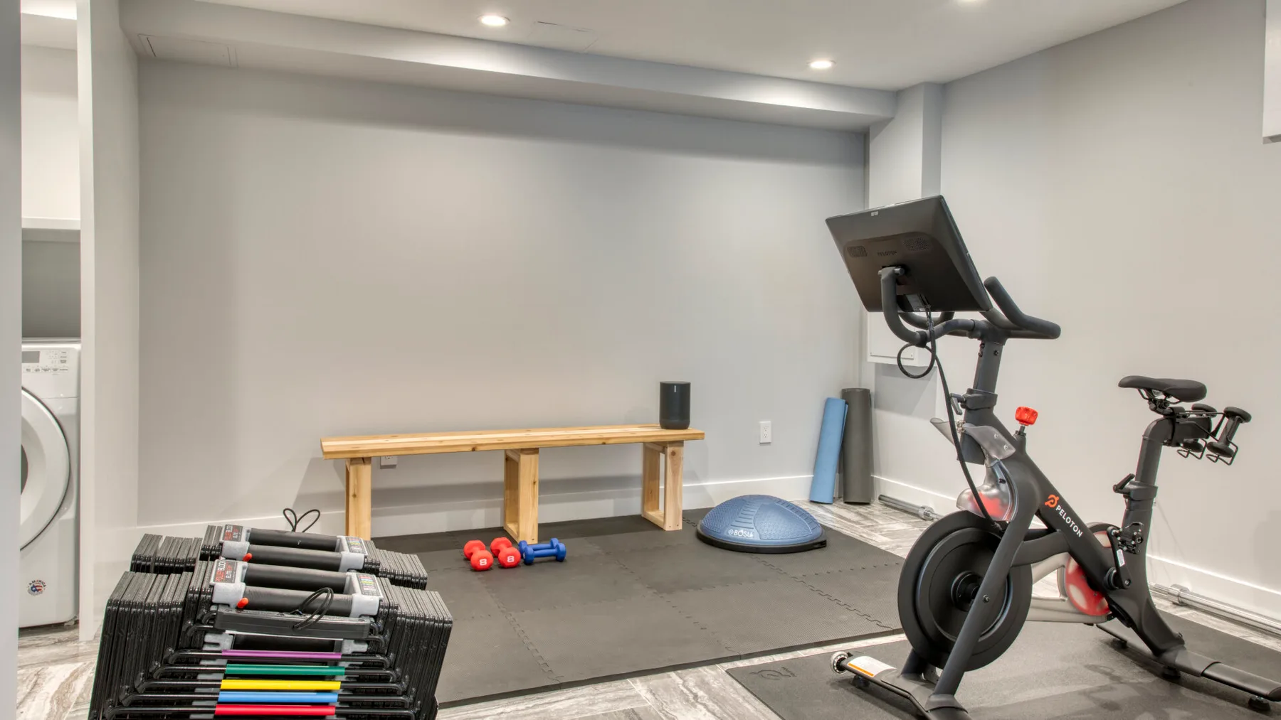 Una zona de ejercicio en casa con bicicletas estáticas, pesas y un disco de equilibrio.
