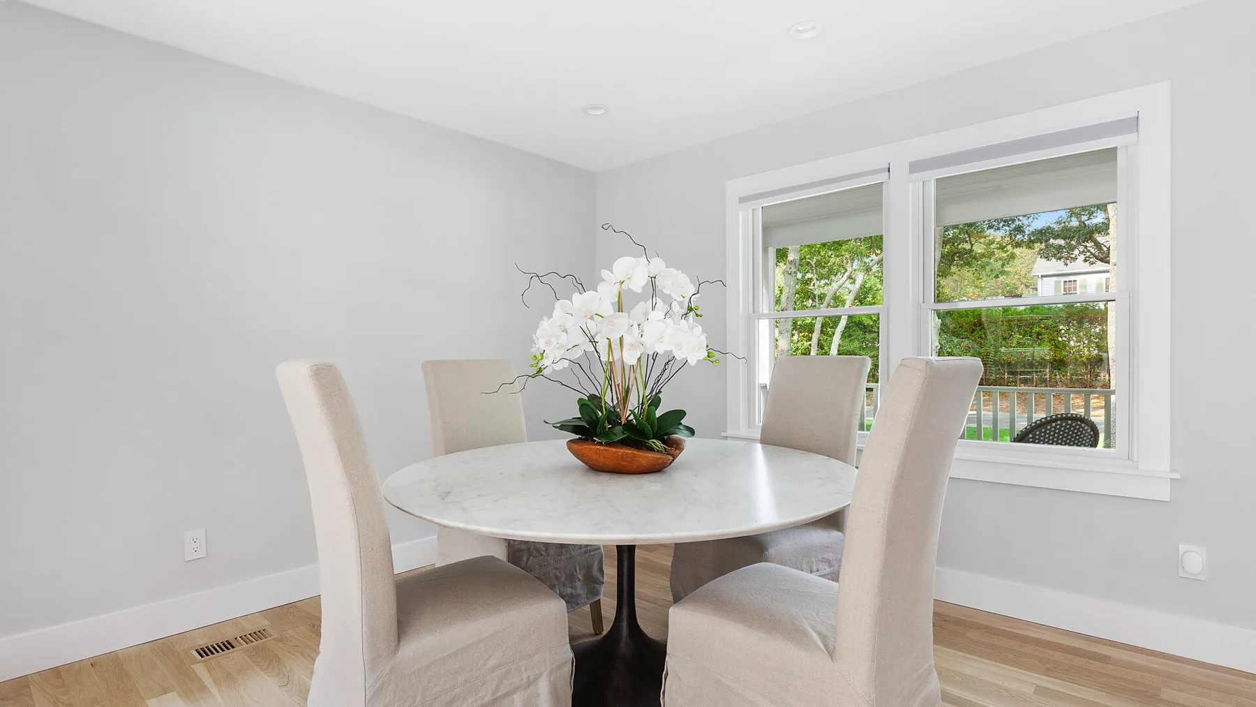 Un comedor con una mesa redonda, asientos tapizados y un arreglo floral.