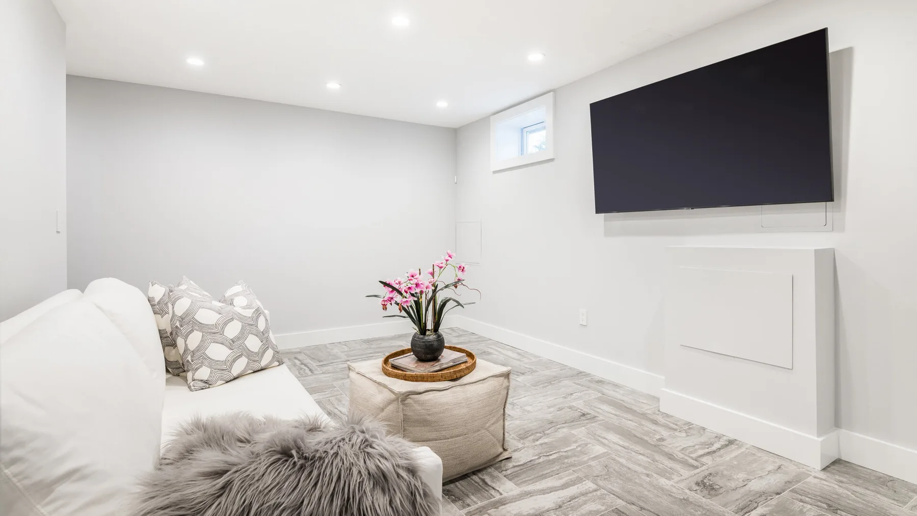 Una sala luminosa con un televisor montado en la pared y asientos acolchados.
