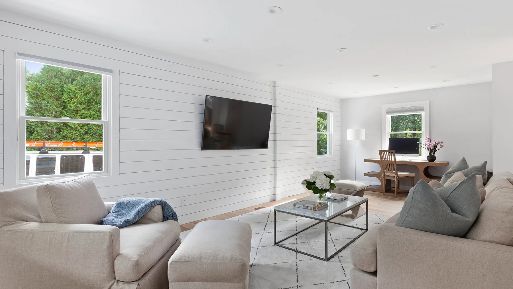 Una sala luminosa con asientos, un televisor en la pared y una mesa de centro de vidrio.