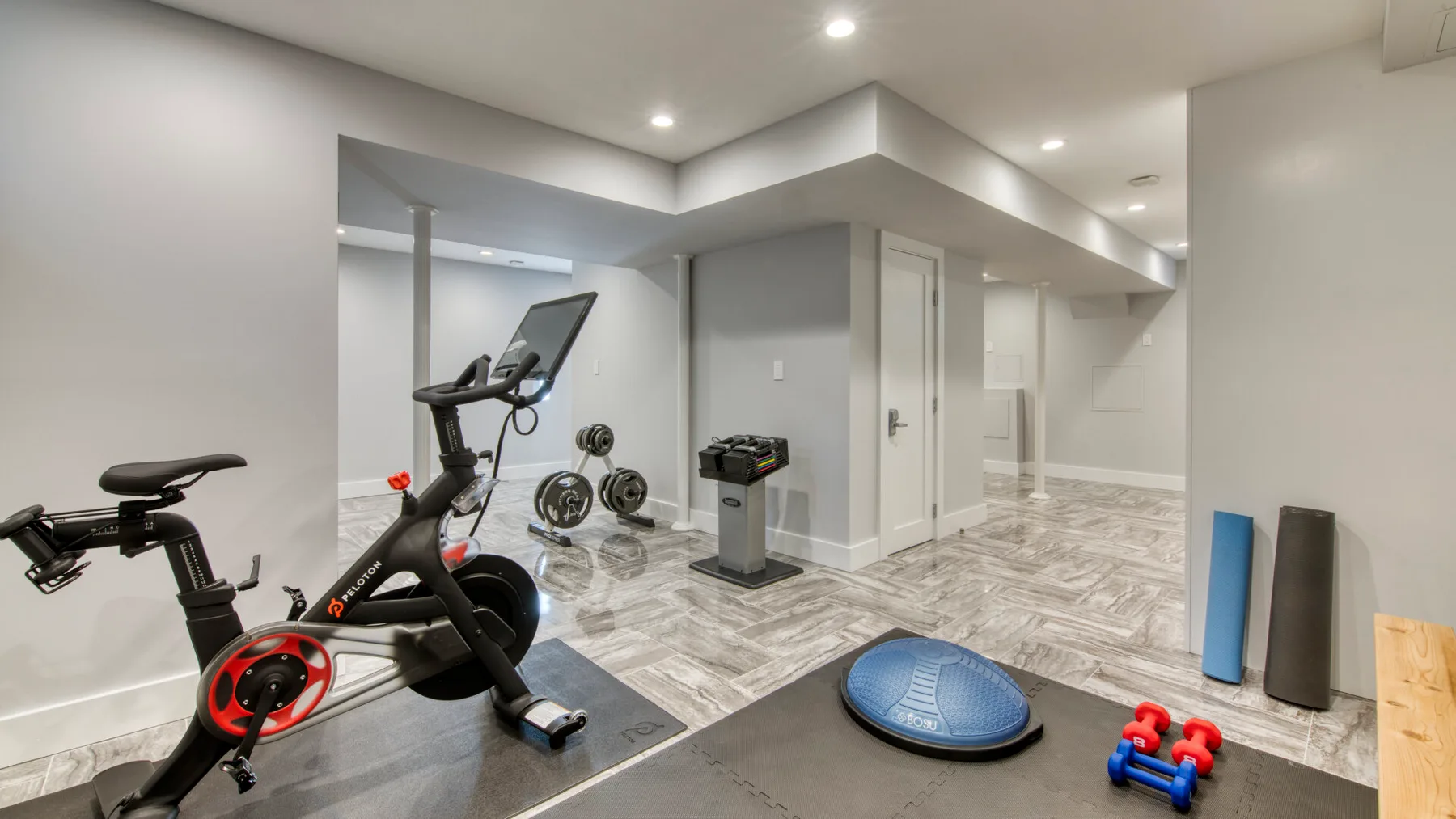Zona de ejercicio en casa con bicicleta estática, pesas y un entrenador de equilibrio.