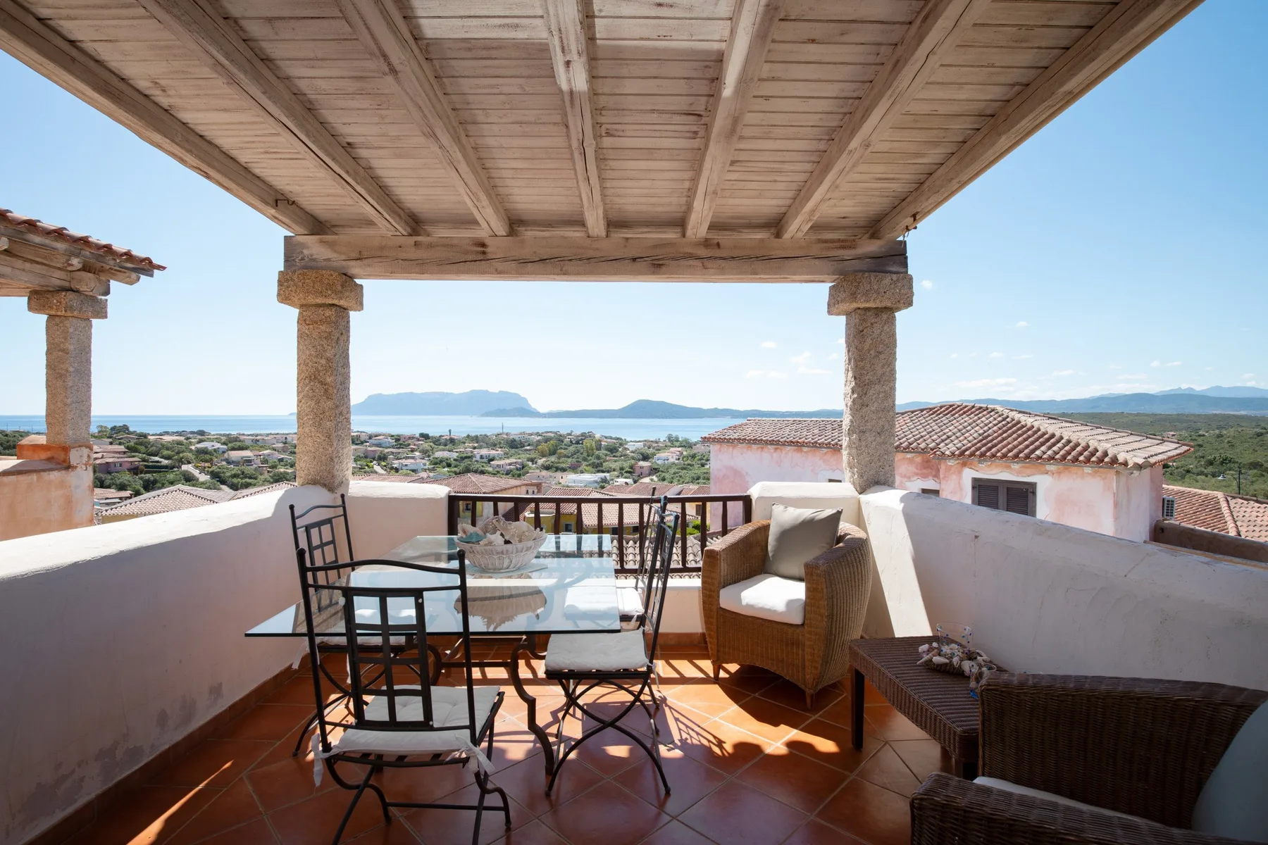 A covered terrace with seating and a view over nearby rooftops.