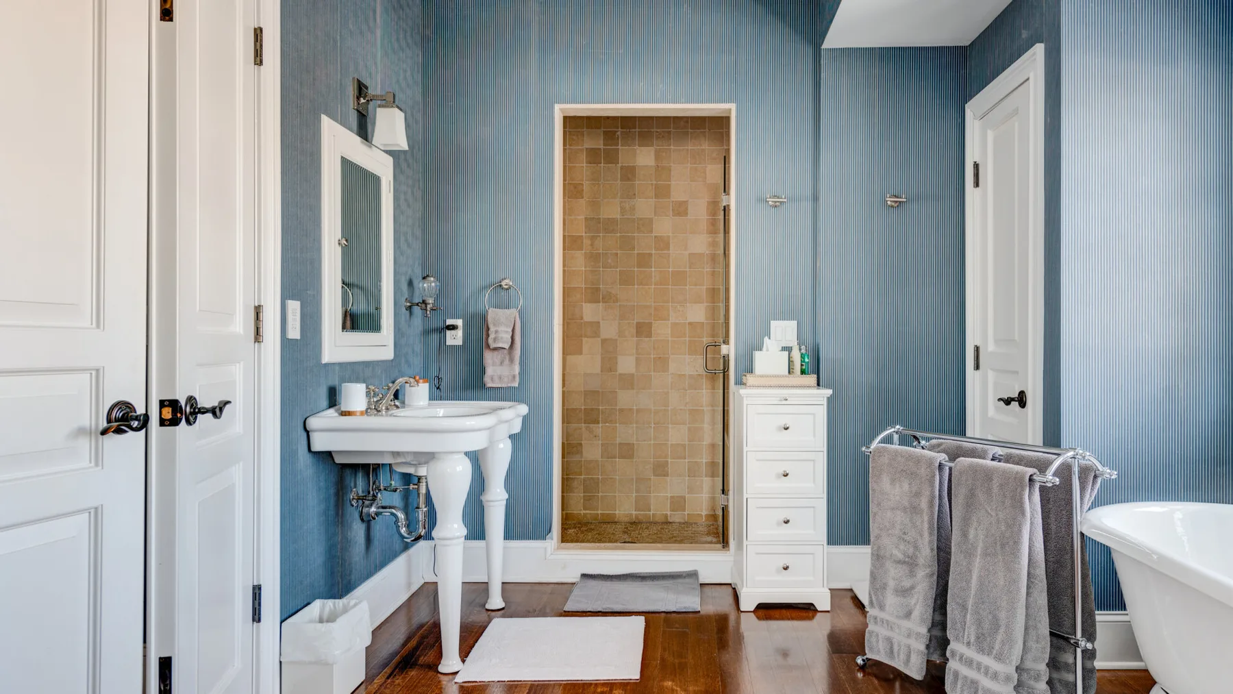 Un baño con ducha de azulejos, lavabo y bañera exenta.