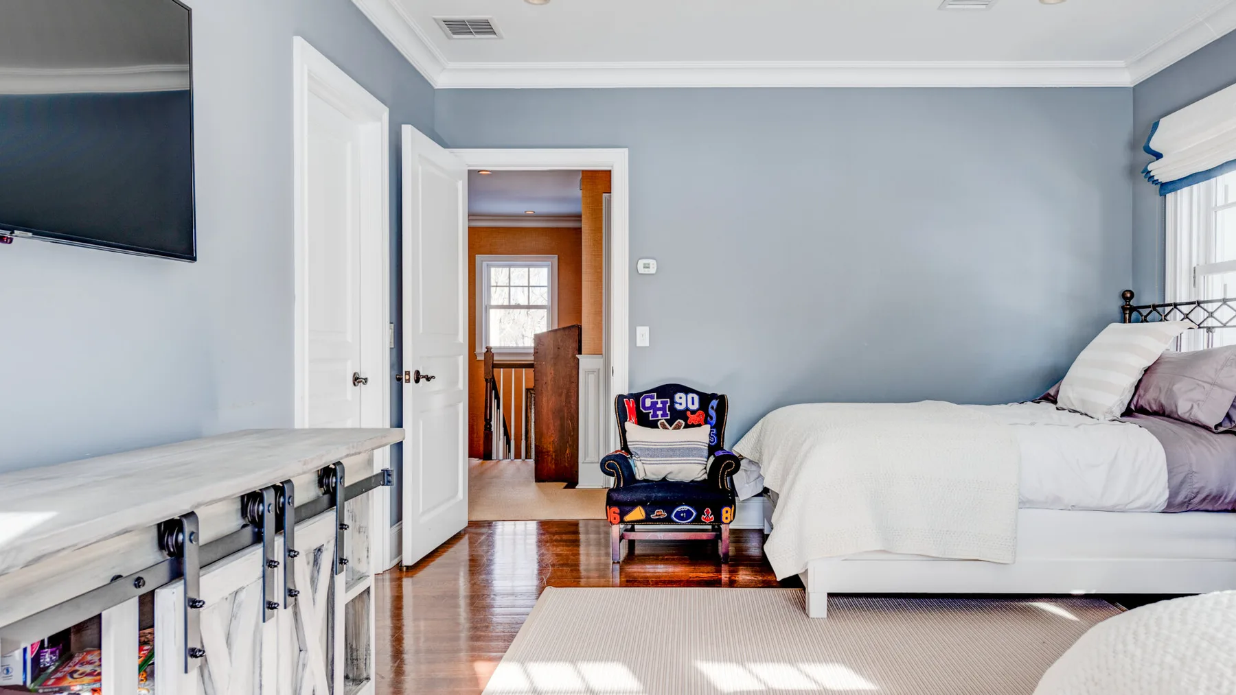 Un dormitorio con una cama, un televisor y una silla pequeña.