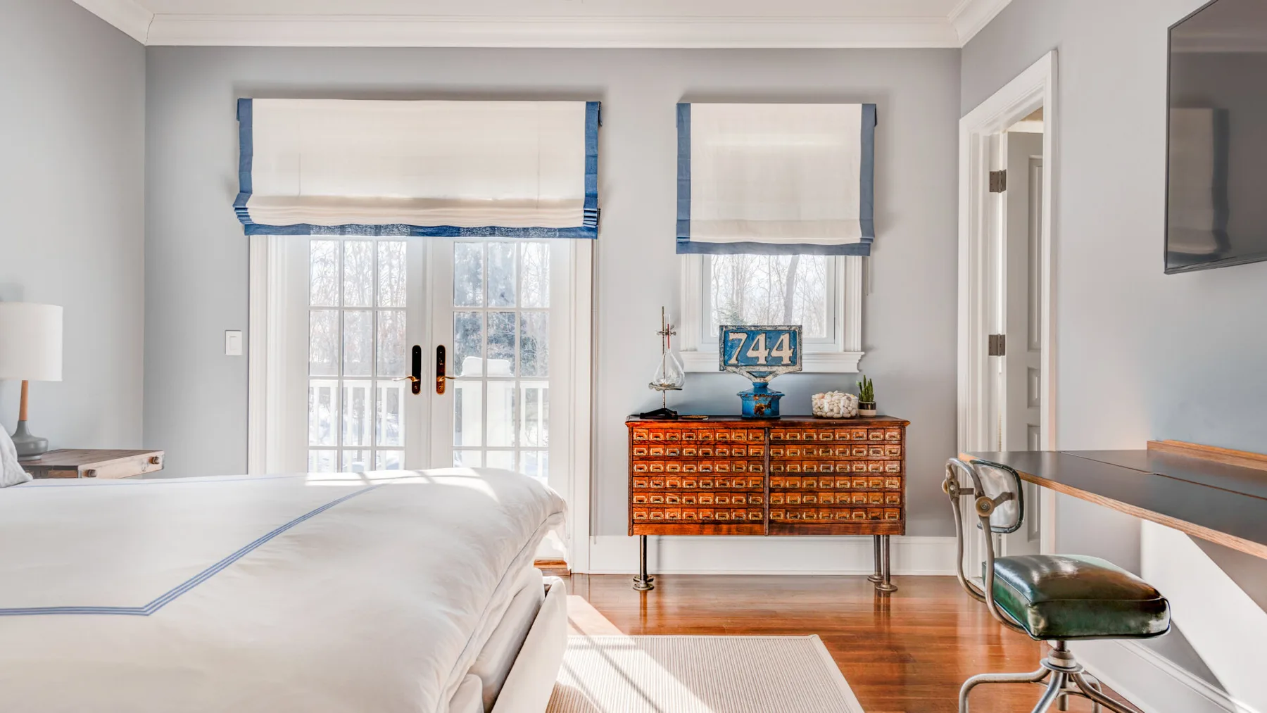 Un dormitorio con una cama, ventanas y una cómoda.