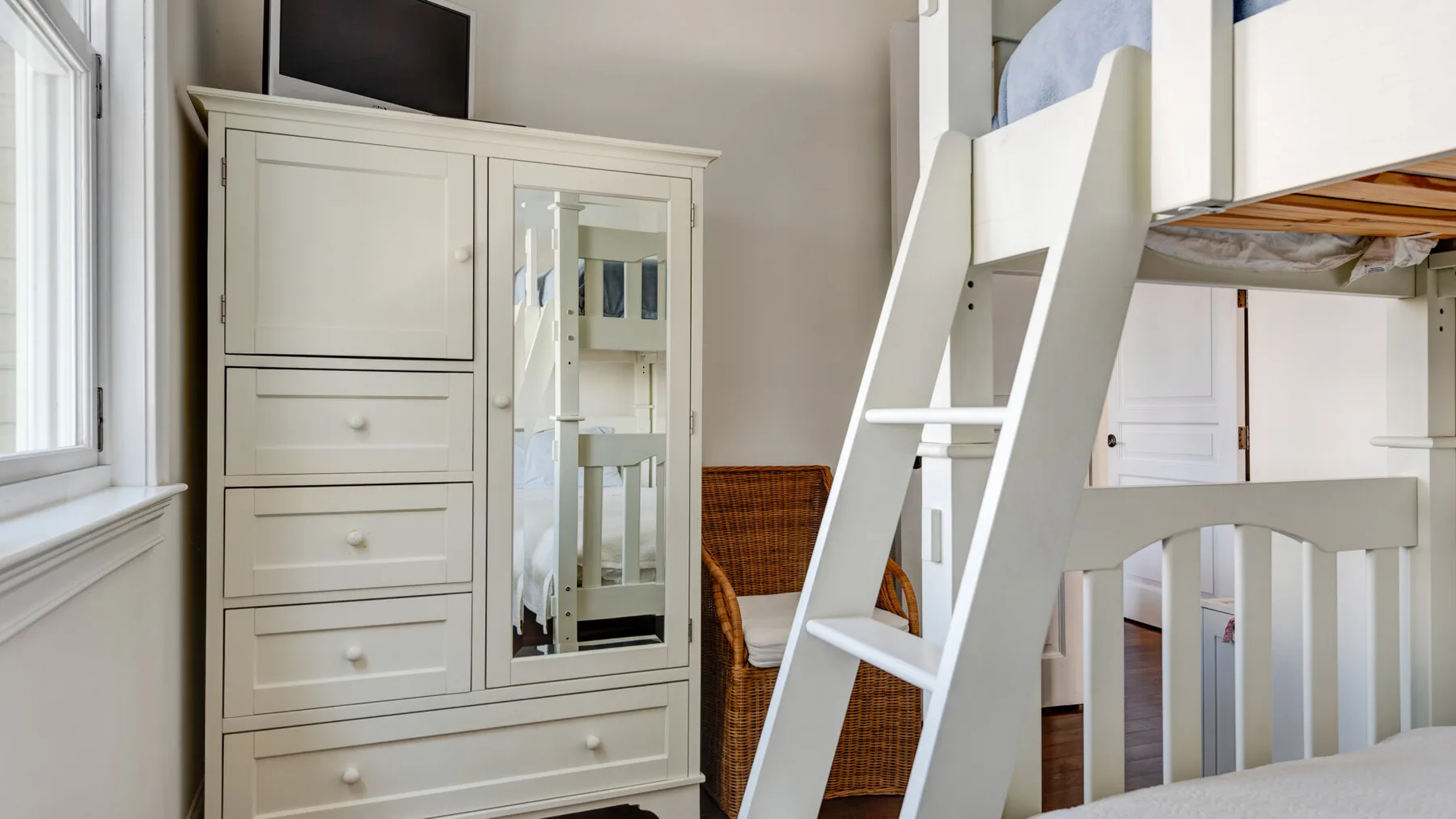 Un dormitorio con una litera blanca y una cómoda alta blanca.