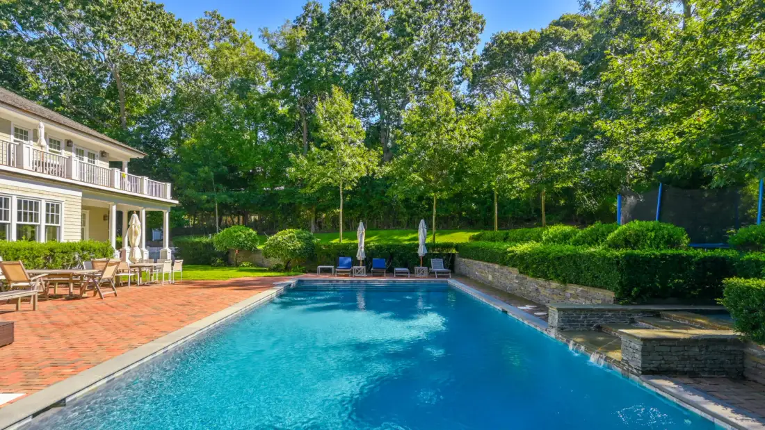 Una piscina al aire libre junto a un patio de ladrillo y una casa.