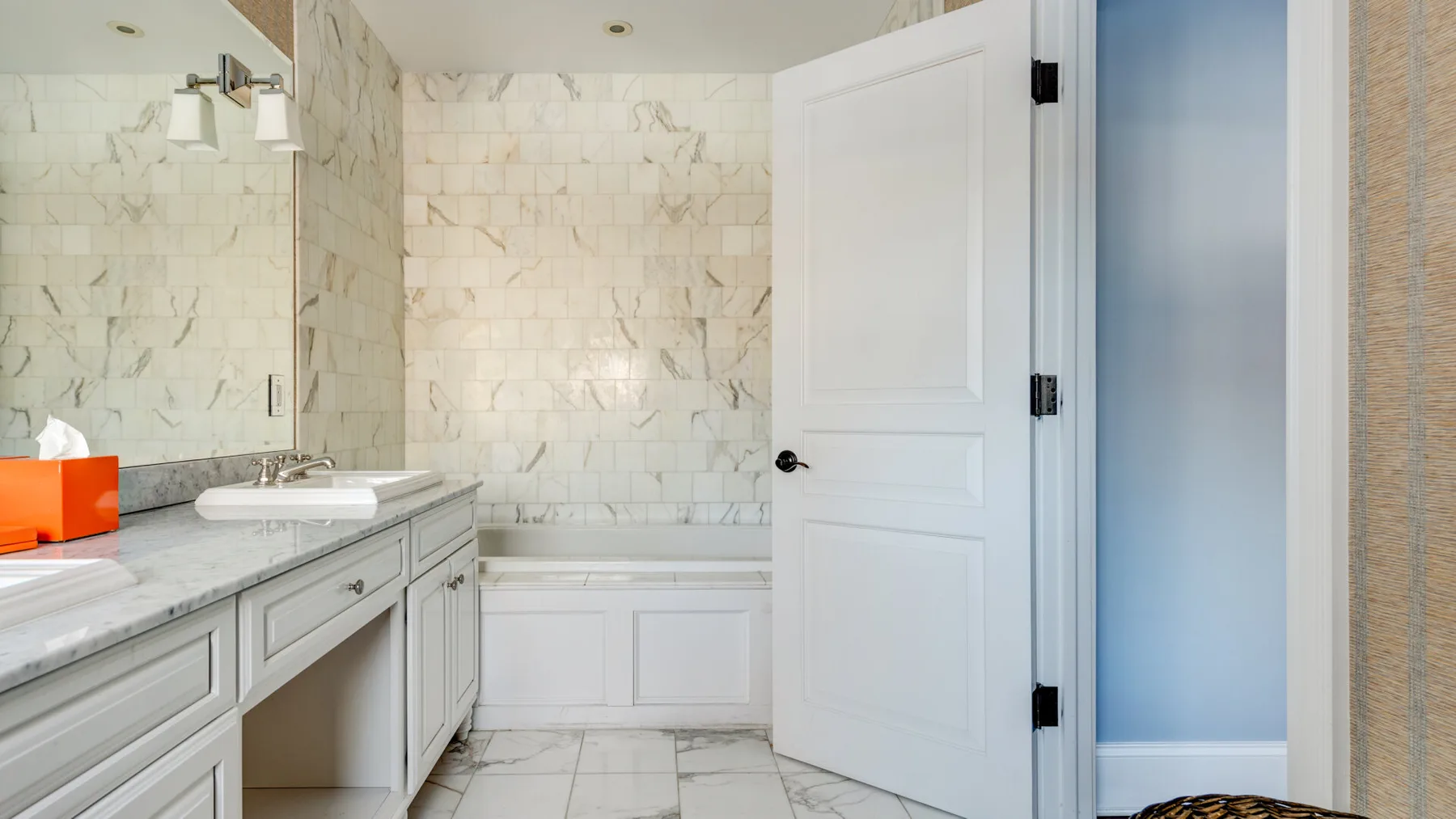 Un baño con azulejos de mármol, lavabo y bañera.