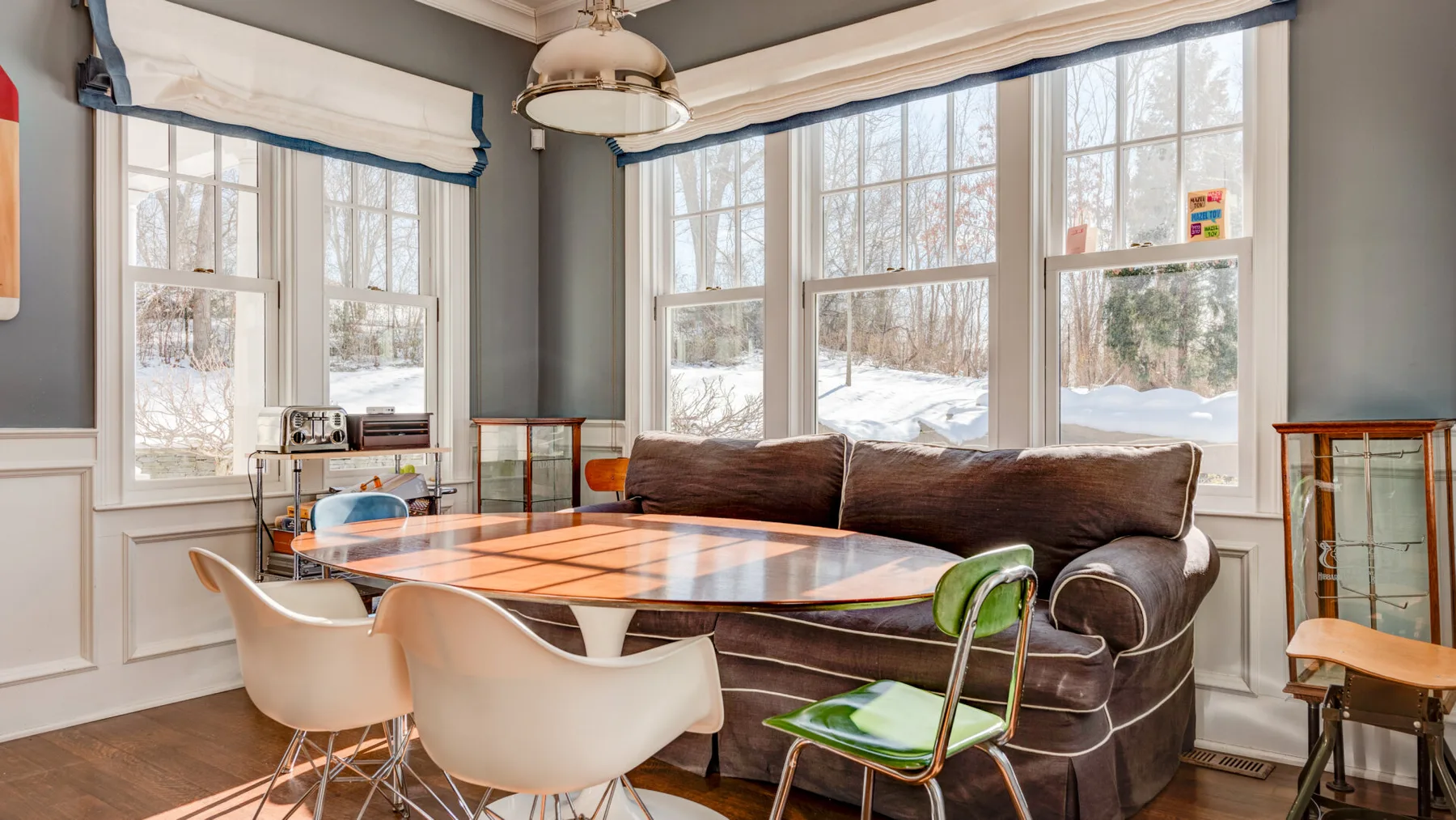 Un comedor con una mesa y asientos junto a grandes ventanas.