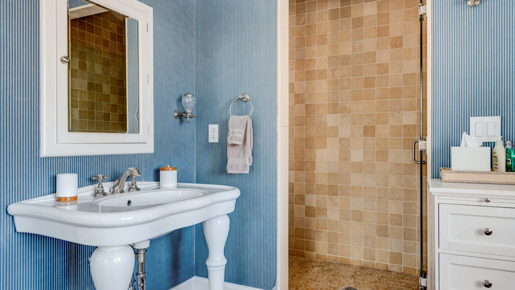 Un baño con un lavabo junto a una ducha con azulejos.
