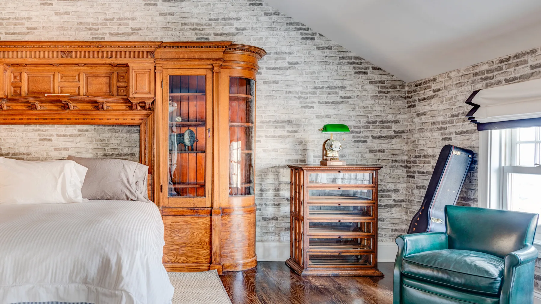 Un dormitorio con una cama, un mueble de madera y un sillón verde.