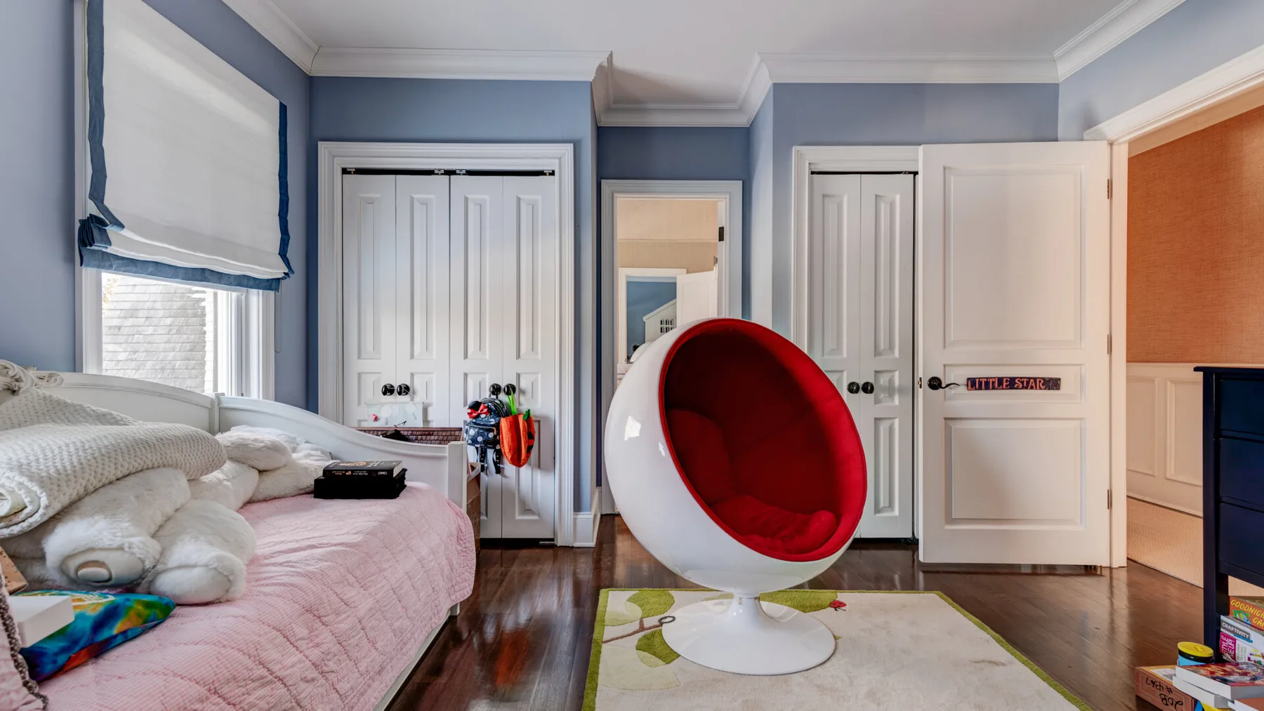 Un dormitorio con una cama y una silla redondeada roja y blanca.
