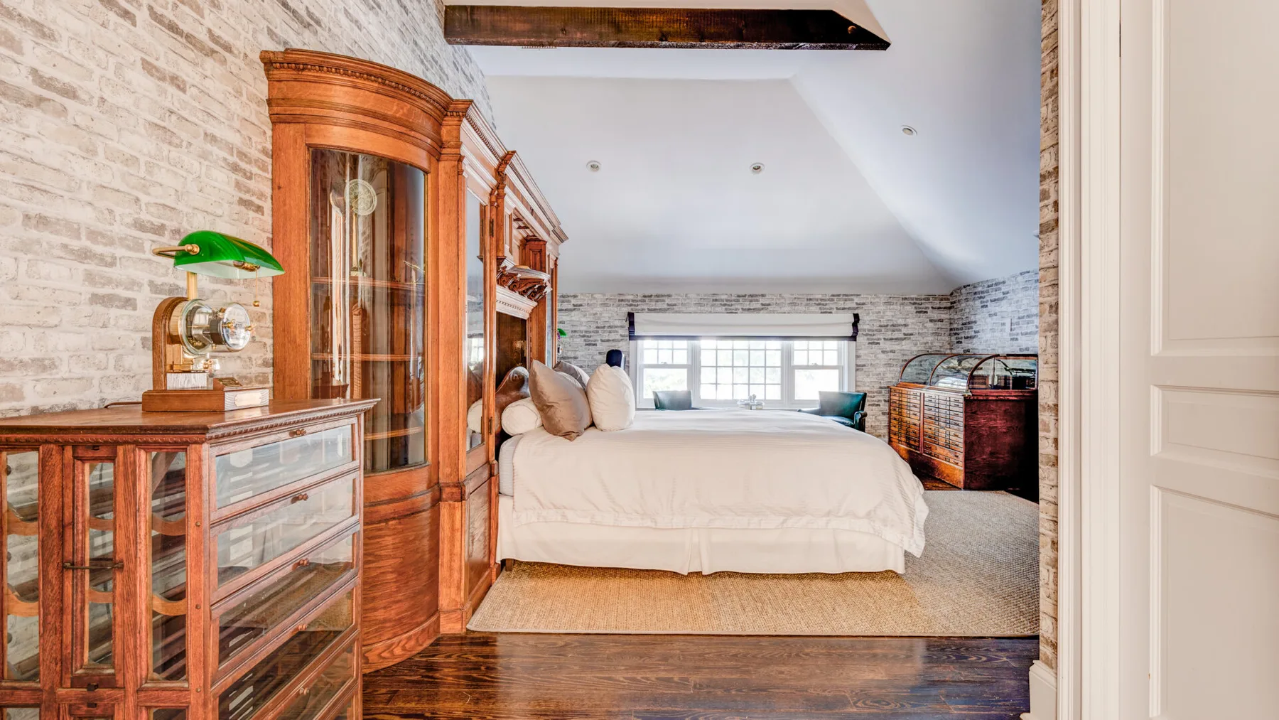 Un dormitorio con una cama, armarios de madera y una ventana al fondo.